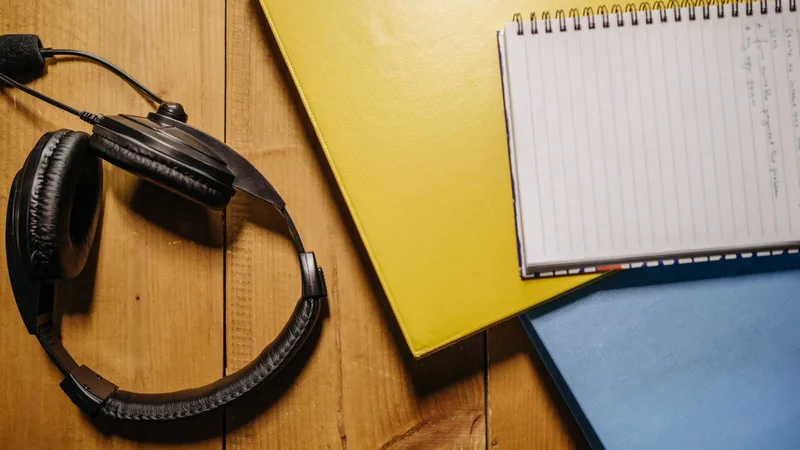 Headphones resting beside an open spiral notebook on a wooden desk